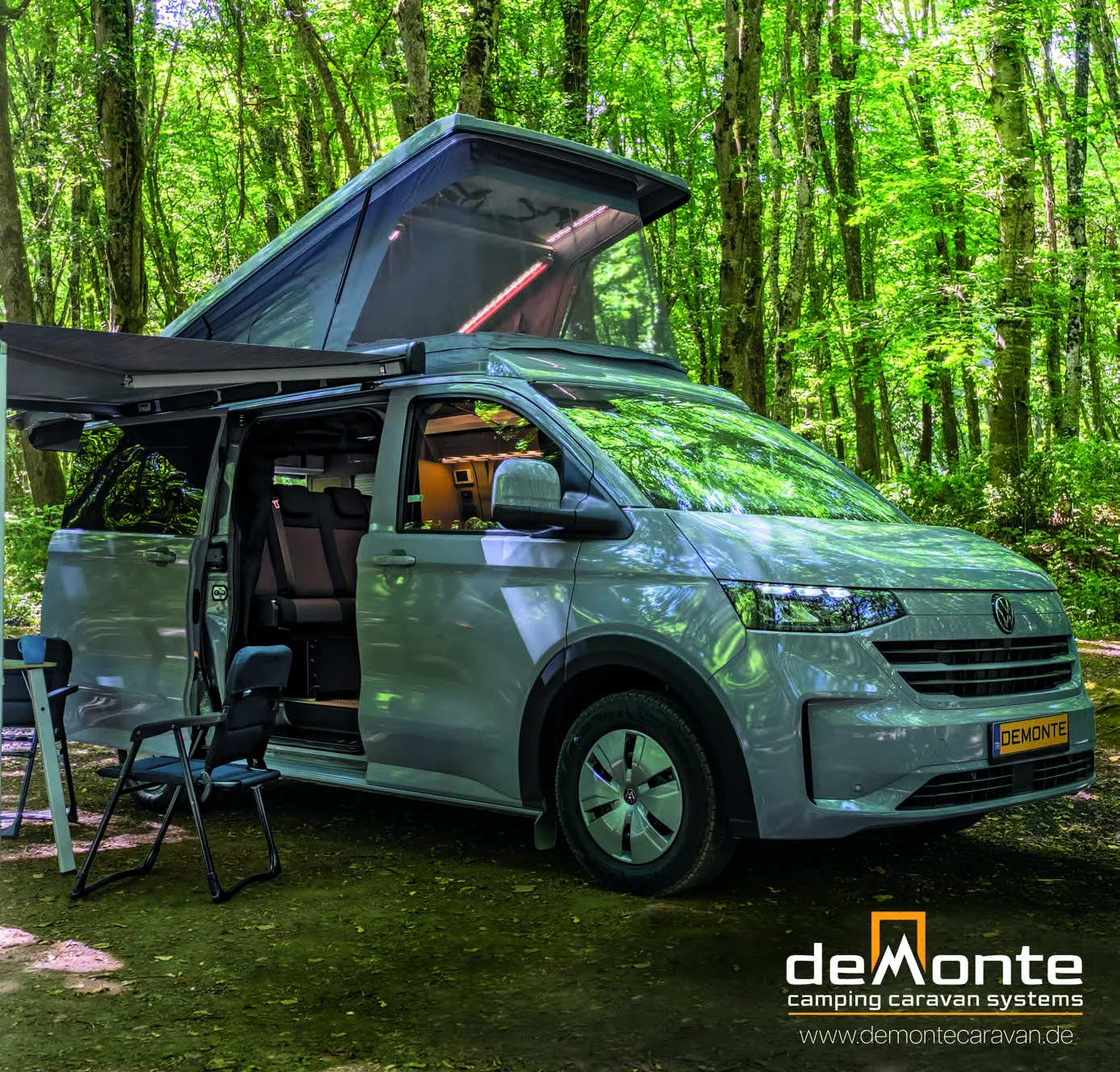 Demonte Caravan Katalog 2026, Seite 1: Titelseite — ein VW Transporter im Wald mit geöffnetem Aufstelldach und Markise, daneben ein Campingstuhl