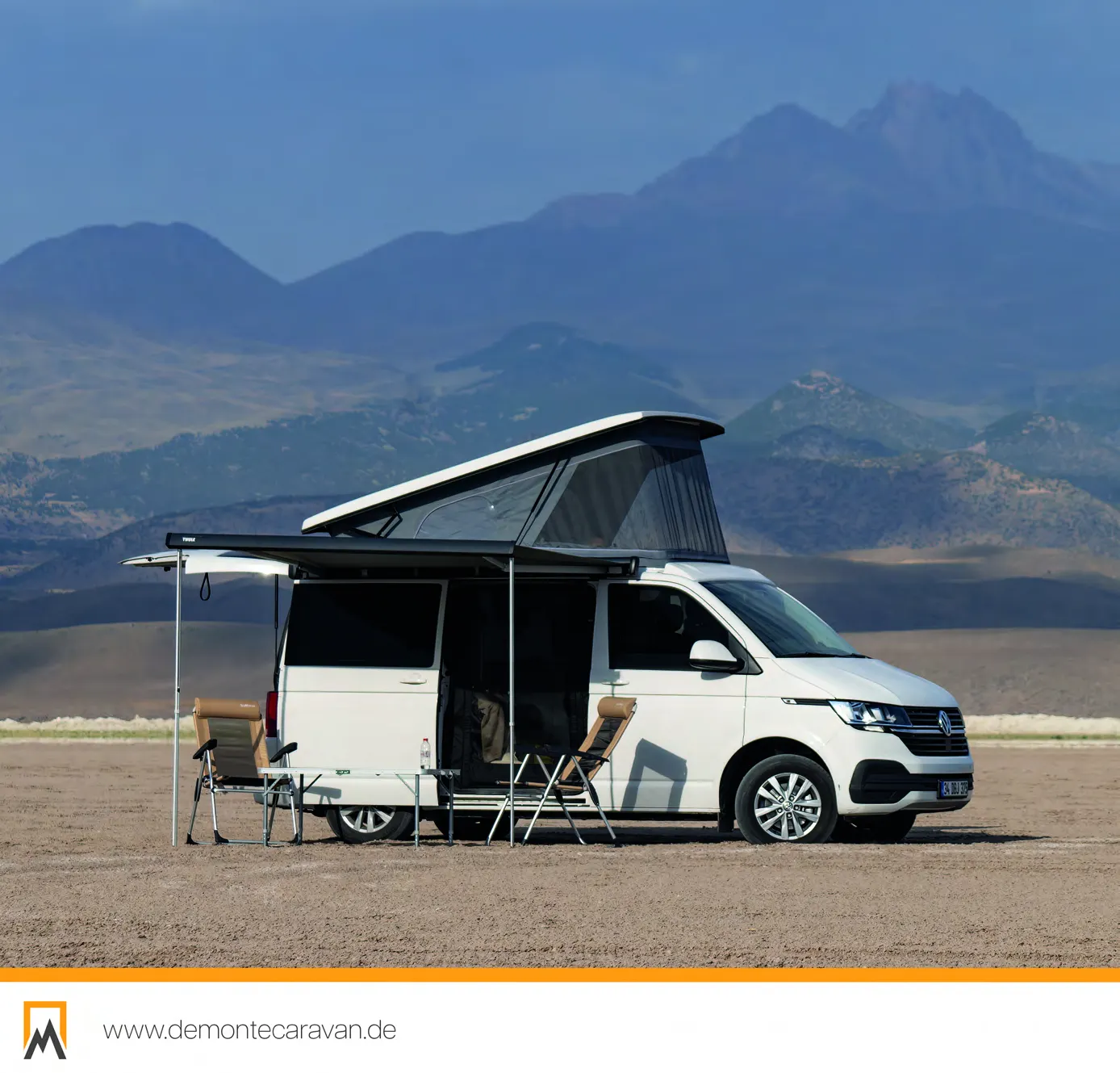 Demonte Caravan Katalog 2026, Seite 16: ein weißer VW Transporter mit ausgefahrener Markise und aufgebautem Camp vor einer Bergkulisse